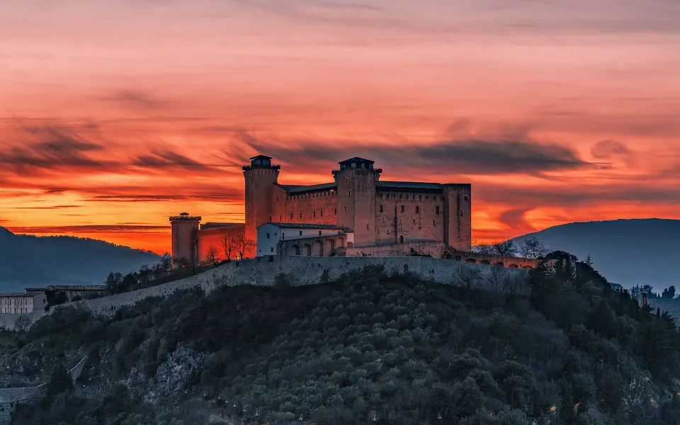 La Rocca Albornoz sulla collina al tramonto, con il cielo rosso e arancione