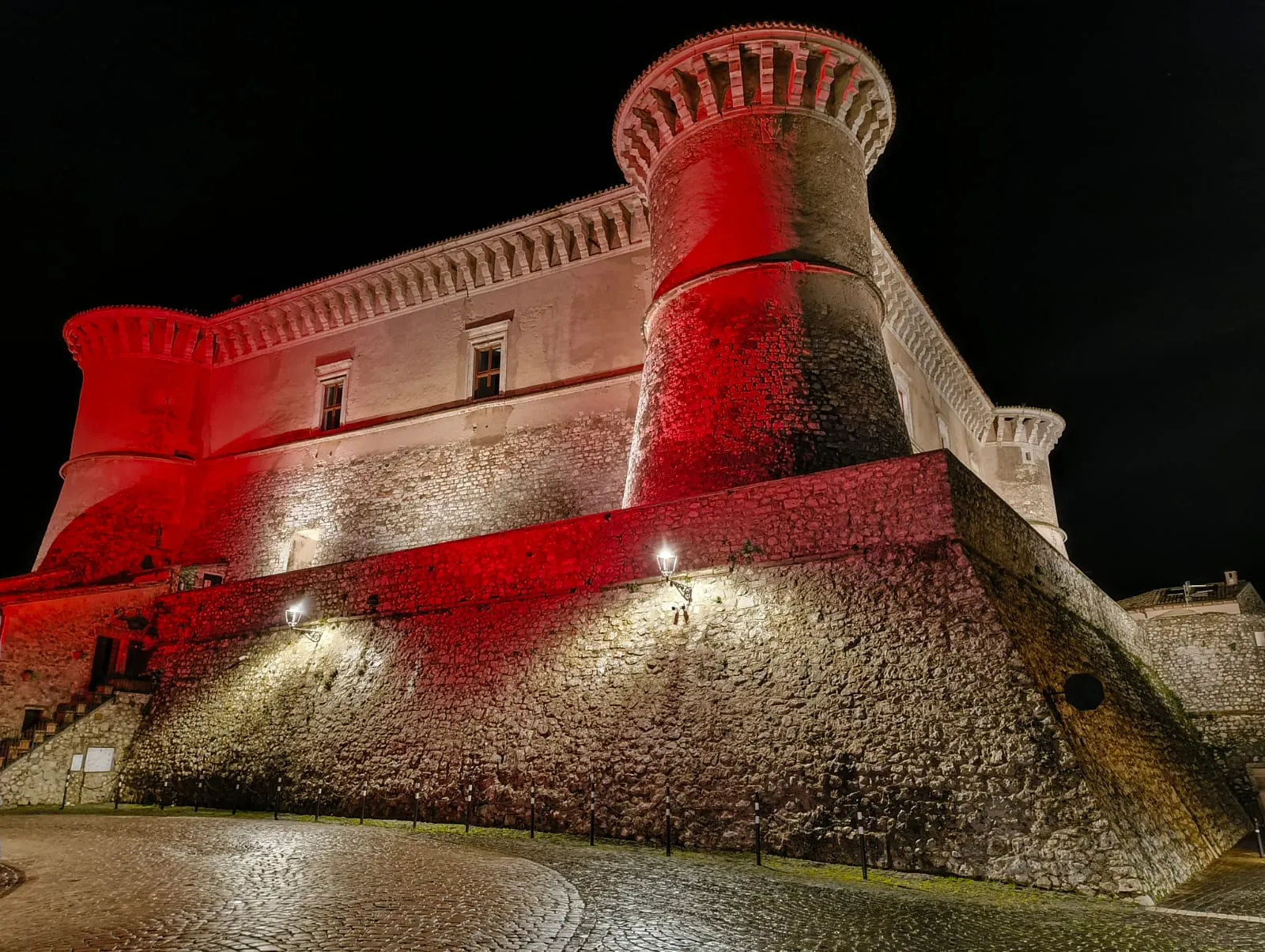 Il torrione angolare del Castello di Alviano illuminato di rosso nella notte